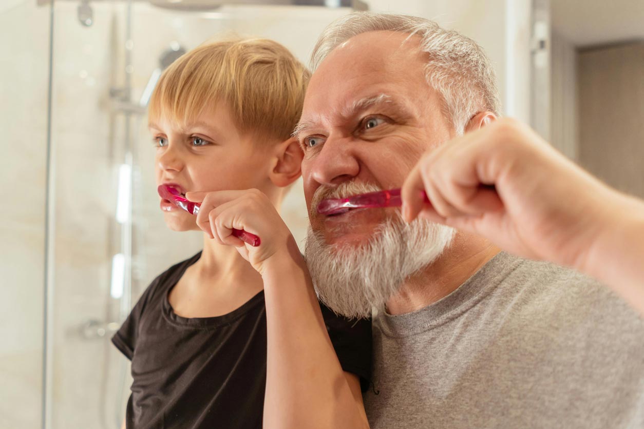 A senior and a young boy brushing their teeth in a bathroom for seniors.