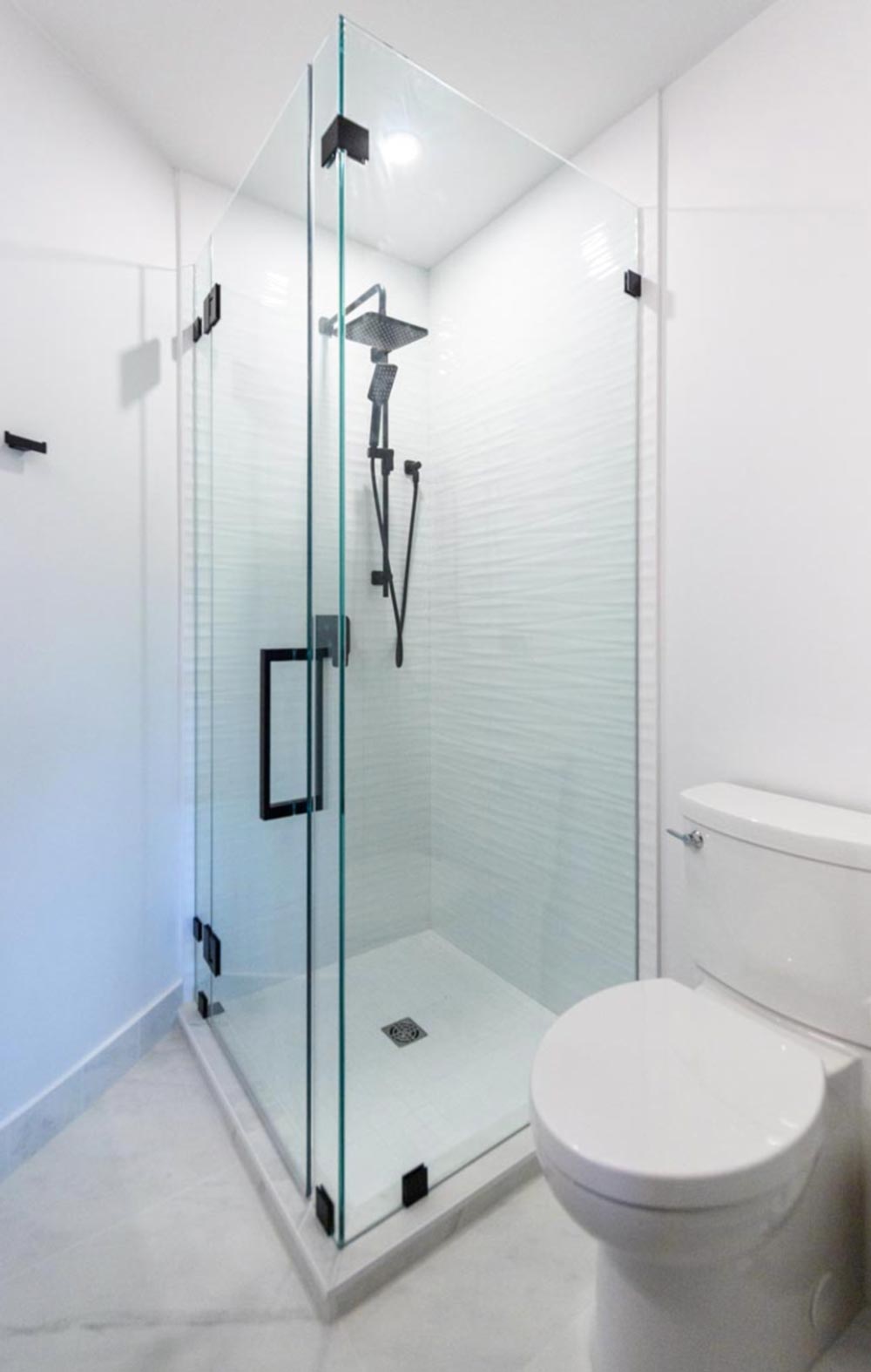 A glass shower enclosure in the corner of a small bathroom