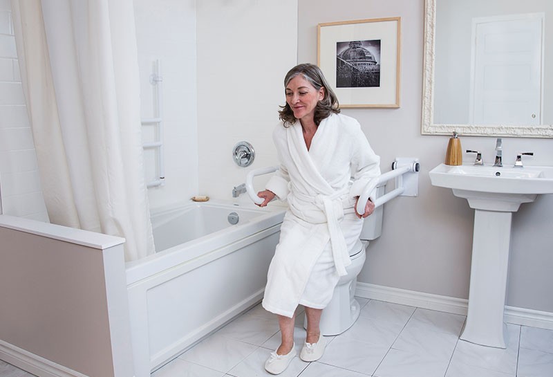 An elderly woman using grab bars in the bathroom